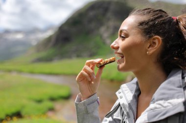 Profile of a hiker eating a cereal bar in the mountain