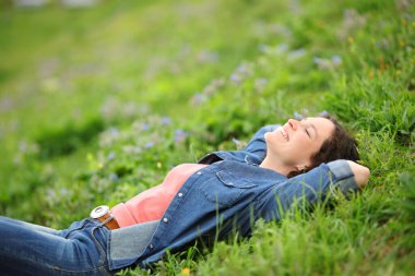 Woman lying on the grass in a park relaxing and resting 