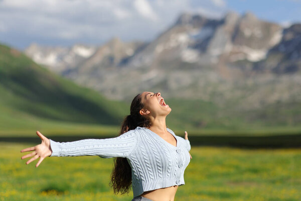 Excited casual woman screaming and outstretching arms in the mountain