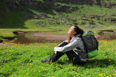 Hiker resting and breathing fresh air sitting on the grass in nature