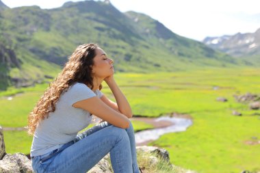 Profile of a woman relaxing isitting n a mountain valley