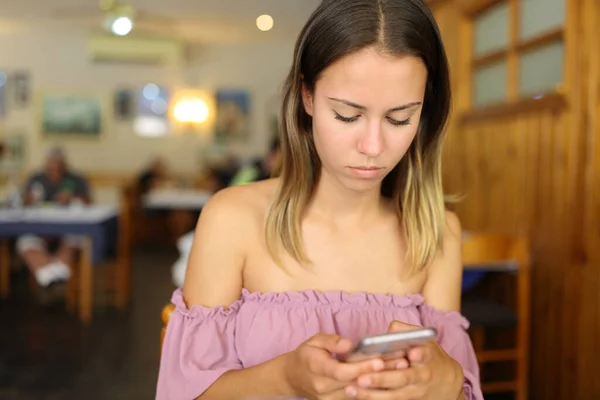 Concentrated woman in a restaurant using smart phone
