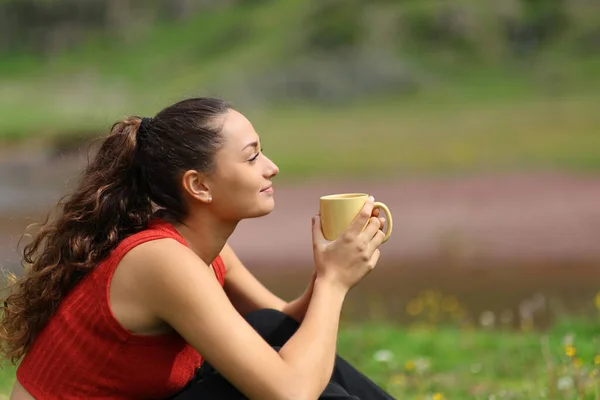 Profile of a woman drinking coffee in the mountain looking away