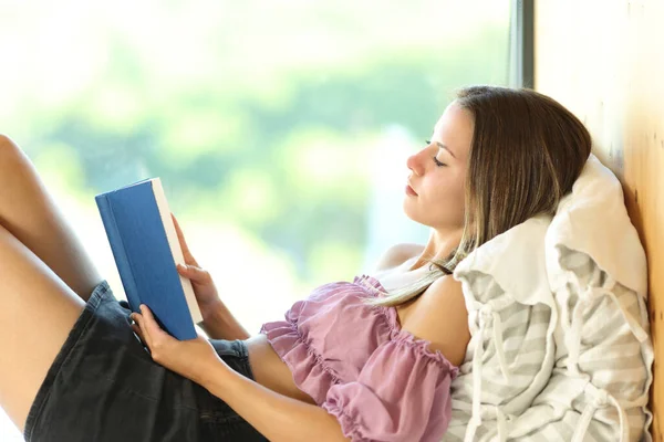 Profil Kobiety Czytającej Książkę Leżącą Obok Okna — Zdjęcie stockowe