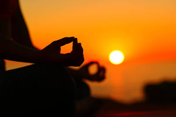 日落时在海滩上做瑜伽的瑜伽手的背光轮廓 — 图库照片