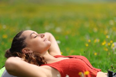 Rahatlamış bir kadın yazın dağda bir tarlada dinleniyor.