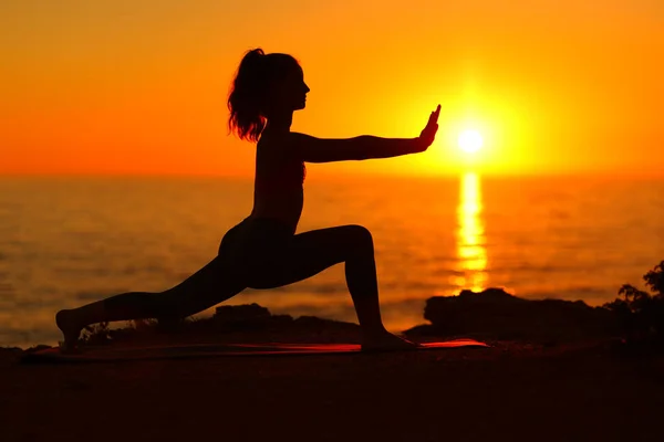 一个女人在日落时在海滩上做太极拳的轮廓 — 图库照片