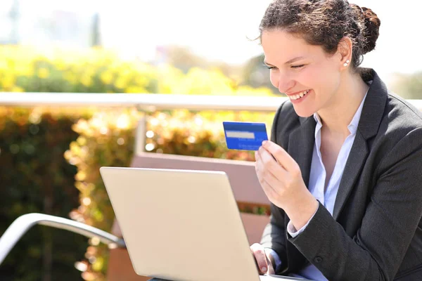 快乐的女商人坐在公园里 用信用卡和笔记本电脑在网上支付 — 图库照片