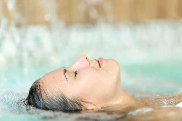 Profile of a woman floating and relaxing in a spa pool