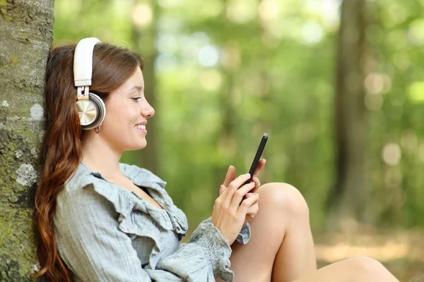 Профиль Счастливой Женщины Слушающей Музыку Наушниках Смартфоне Отдыхающей Лесу — стоковое фото