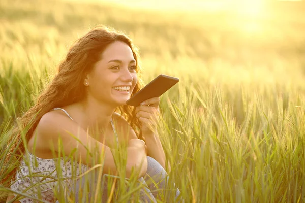 日落时分 快乐的女人在麦田里的智能手机上使用语音识别 — 图库照片