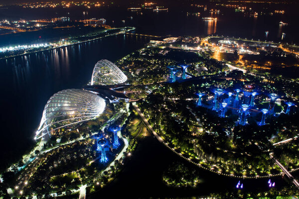 SINGAPORE - NOVEMBER 7, 2017: a panoramic view of the Gardens by the Bay with it's Supertrees and the two famous greenhouses, seen from the Marina Bay Sands Skypark observation deck during the night.