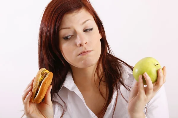 Молодая женщина с гамбургером и яблоком — стоковое фото