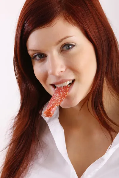 Молода жінка їсть ковбасу — стокове фото