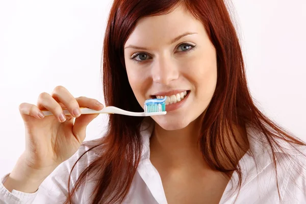 Güzel bir kadın ve bir diş fırçası ve diş macunu kullanılarak — Stok fotoğraf