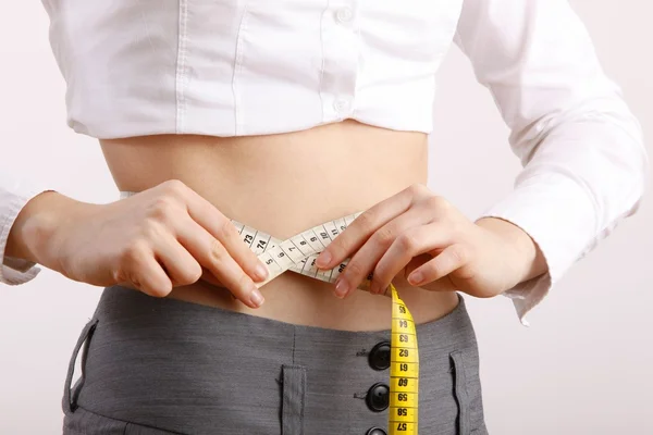 Fit beautiful woman holding measure tape around her stomach. — Stock Photo, Image