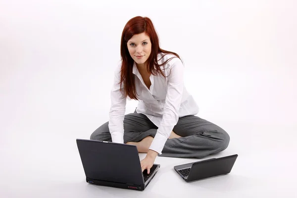 A businesswoman is using her laptops sitting on the ground. — Stock Photo, Image
