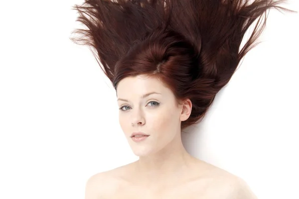 Retrato de uma jovem mulher com o cabelo levemente balançando no vento em um fundo branco — Fotografia de Stock