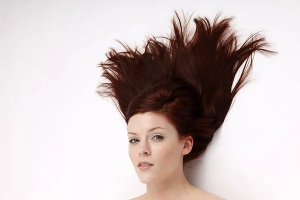 Retrato de uma jovem mulher com o cabelo levemente balançando no vento em um fundo branco — Fotografia de Stock