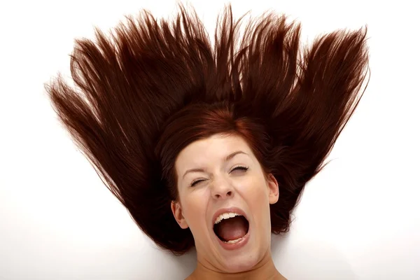 Portret van een jonge vrouw met haar licht wapperen in de wind op een witte achtergrond — Stockfoto