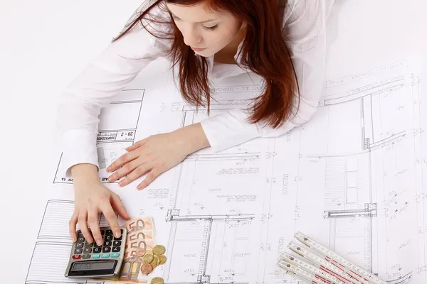 Una mujer trabajando en contabilidad usando calculadora, con dinero Imagen de stock