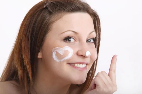 Meisje in handdoek met crème op haar gezicht — Stockfoto