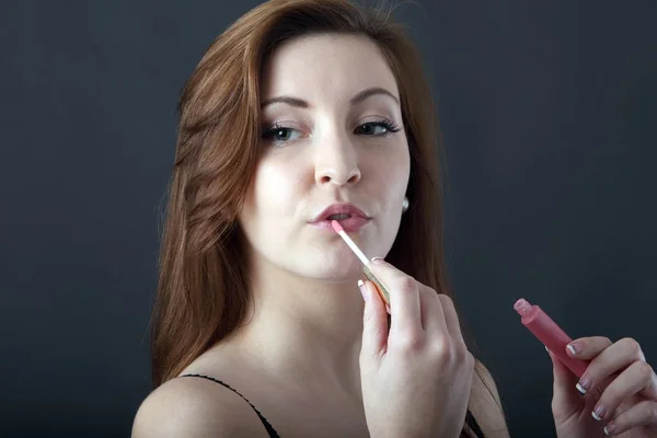 Красивая молодая женщина наносит блеск для губ — стоковое фото