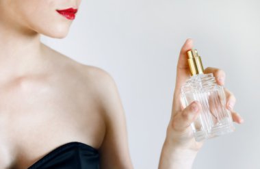 sevimli genç bir kadının elinde bir parfüm şişesi ile Resim kırpılmış.