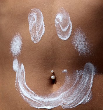 Kız güneş koruyucu karnına koyar.