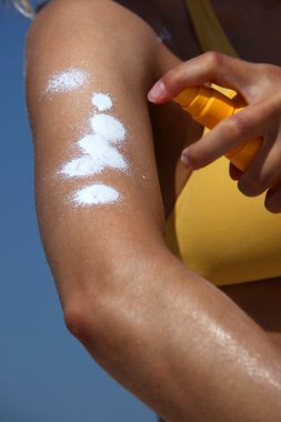 Kız güneş kremi ellerini koyar.