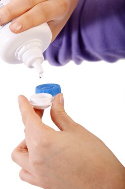 Young woman holding contact lenses cases and bottle of cleaning liquid clipart