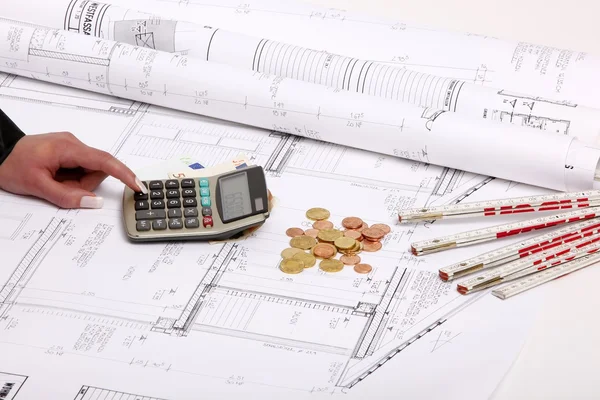 Handen met het plan van de bouw van het huis, rekenmachine, geld, muntstukken — Stockfoto