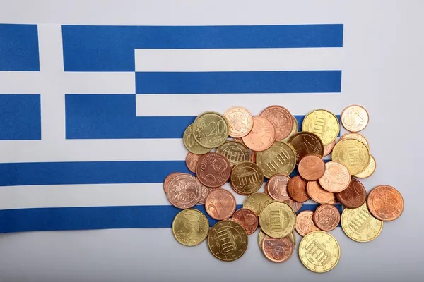 Wrinkled Greek flag burried under Euro coins against a white background — Stock Photo, Image