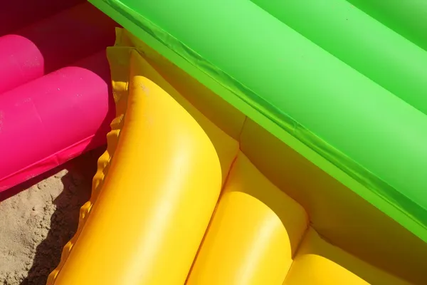 Three colors floating air mattresses on the beach — Stock Photo, Image