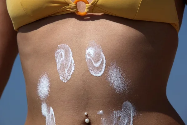 Girl puts sunscreen on her stomach — Stock Photo, Image
