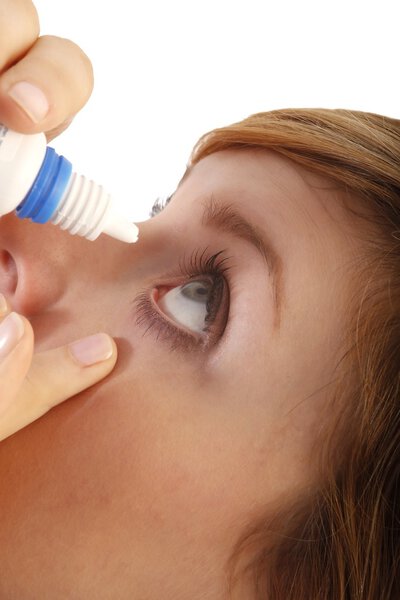 Женщина капает глазами с глазными каплями
