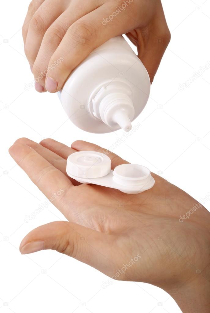 Woman holding contact lenses cases and bottle of cleaning liquid