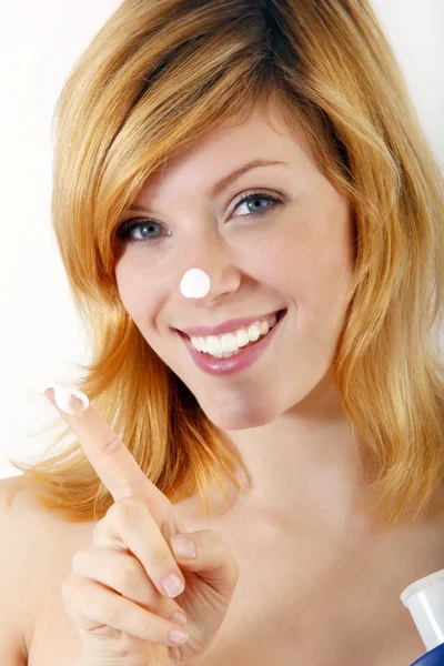 Красива жінка наносить косметичний крем на обличчя — стокове фото