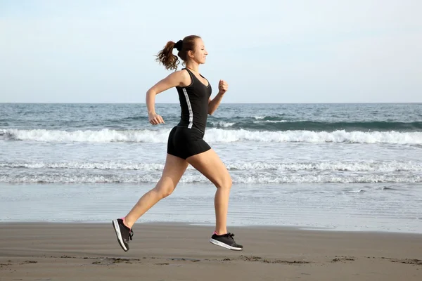 Frau läuft am Strand — Stockfoto