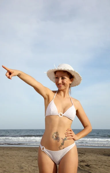 Woman at the beach pointing — Zdjęcie stockowe