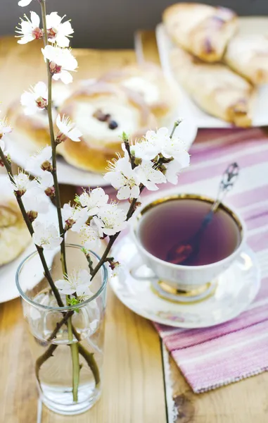Bollos de queso y pasas, taza de té y albaricoque en flor en el jarrón . —  Fotos de Stock