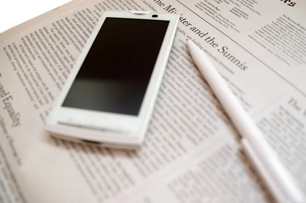 Phone lying on a newspaper — Stock Photo, Image