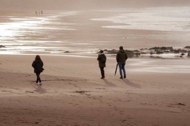 İnsanlar gün batımında Vizcaya 'da Sopelana sahilinde yürürler.