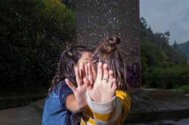 Lezbiyenler yağmurda öpüşüyor ellerini kameranın önüne koyuyorlar.