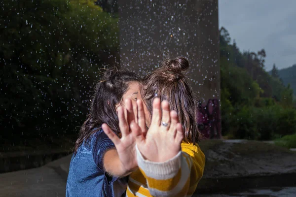 lesbians kissing in the rain putting their hands in front of the camera lens