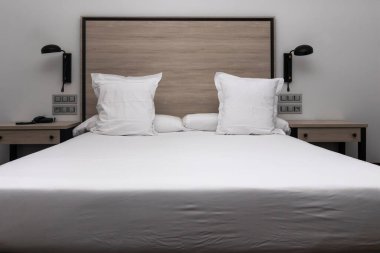 Modern yatak odasında beyaz yataklı büyük boy bir yatak.