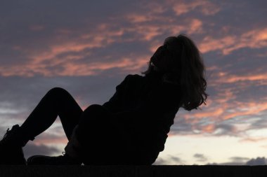 Gün batımında oturan güzel kadın silüeti