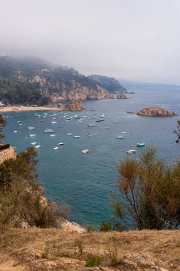 bay of tossa de mar full of boats and tourists one day with fog