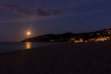 Ufukta dolunay yükselirken gece kumsalda