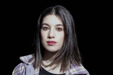 Kameraya siyah arka plan üzerine arayan esmer kadın portresi